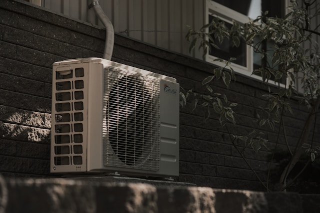 a white air conditioner sitting on top of a brick wall